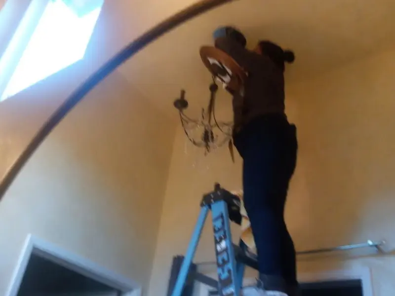 Electrician installing a chandelier in a Sulphur residence